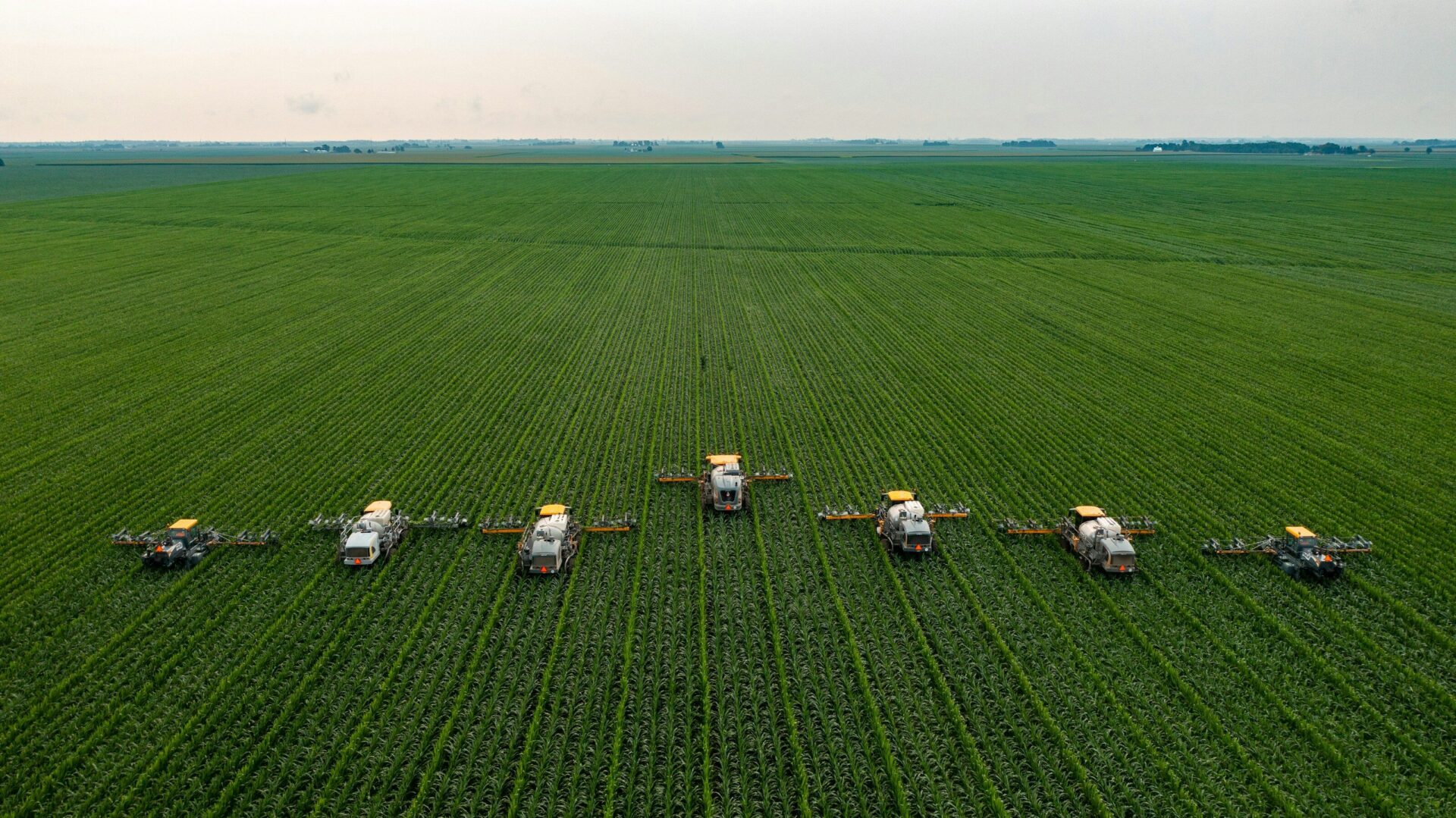 white and black tractors on green grass field under white sky during daytime